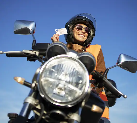Motorradfahrerin mit Helm, Führerschein und Schutzkleidung auf einer Motorradtour.