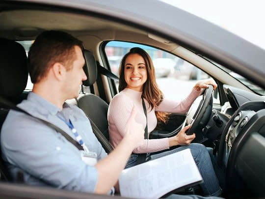 Frau erhält Fahrunterricht bei Fahrschullehrer im Auto, praktische Fahrstunden in der Fahrschule.